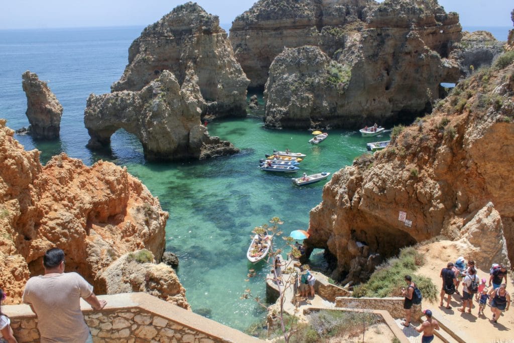Bela vista da Ponta da Piedade, no Algarve. Barquinhos aguardando turistas para o passeio, alguns turistas nas escadas.