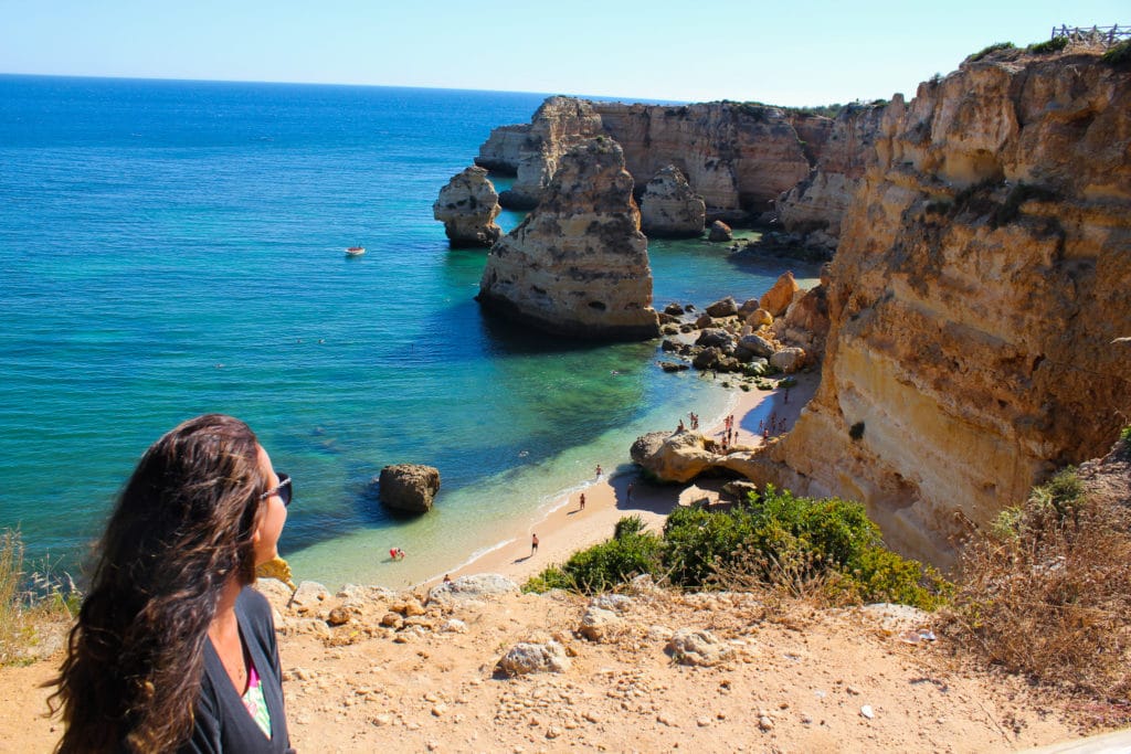 Mulher admirando a praia da Marinha, no Algarve, em Portugal.