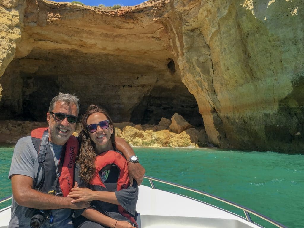 Casal se abraçando em frente a gruta dentro de barco no Algarve