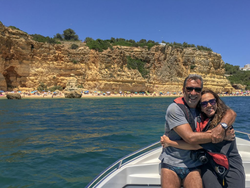 Casal se abraçando em frente à Praia da Marinha, dentro de barco.