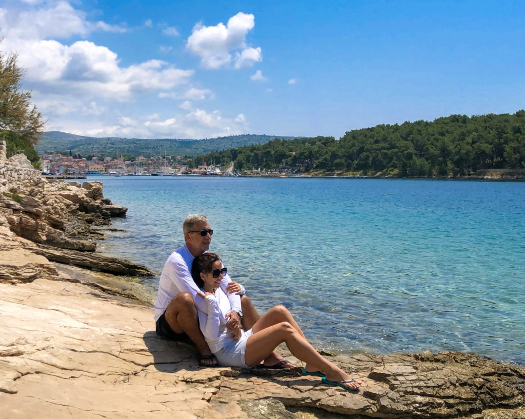 Casal abraçado sentado em pedra perto do mar na Croácia