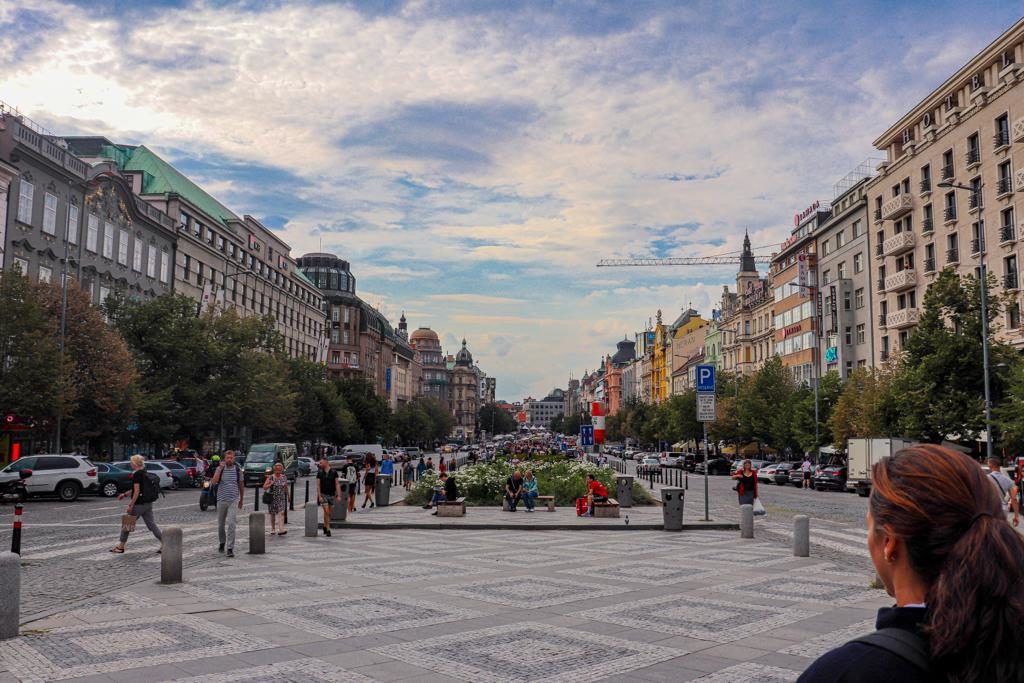 Mulher olhando para prédios em praça de Praga