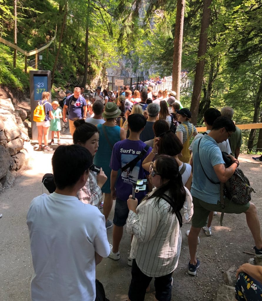 Fila de pessoas para subir na ponte com a vista para o castelo de Neuschwanstein