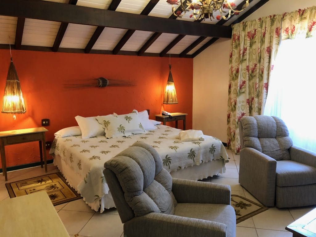 cama king size, suas poltronas reclináveis, mesa de cabeceira do quarto do hotel com hidro e piscina em Teresópolis