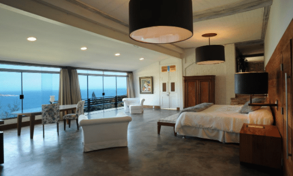 quarto com cama, poltronas e mesa de mansão de novela