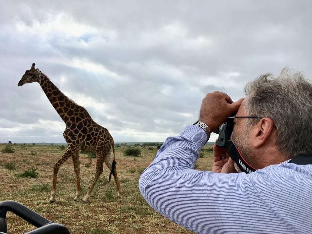 Homem fazendo fotografia de girafa em safári na África do Sul 