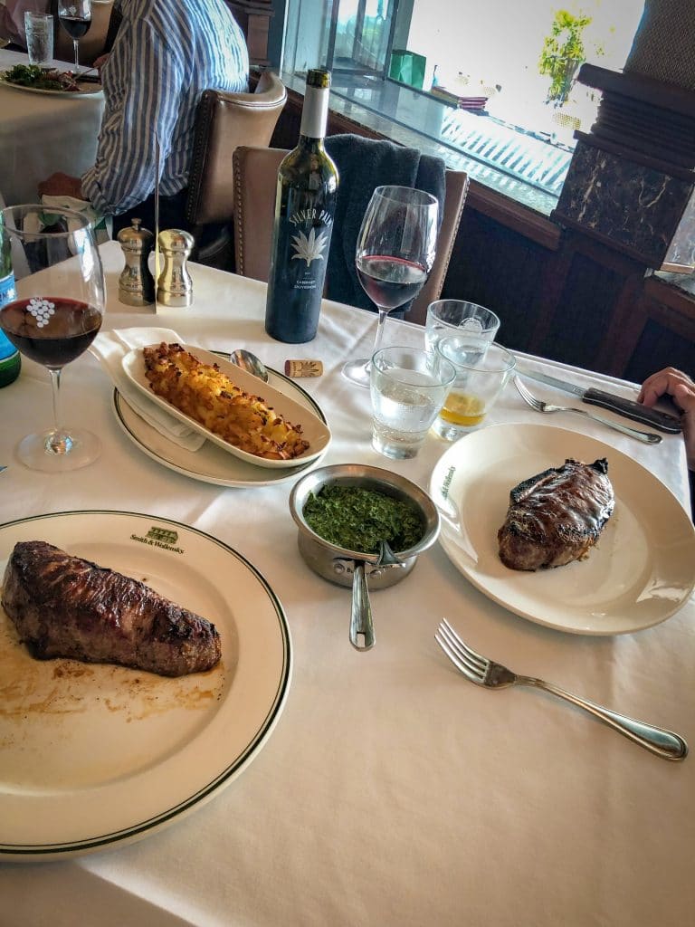 Mesa com duas carnes, vinhos e alguns acompanhamentos em Miami