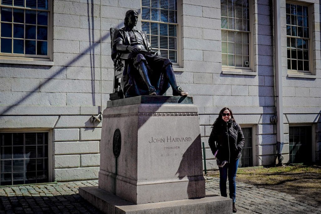 Mulher ao lado de estátua de John Harvard em Cambridge