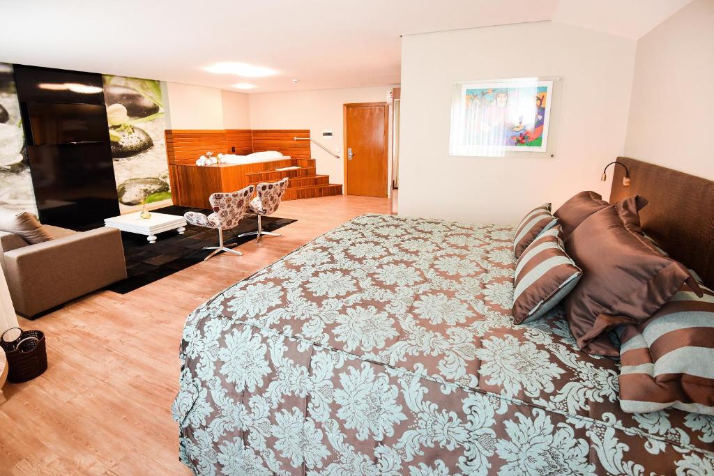Quarto com cama grande e área de lazer com sofá e poltronas