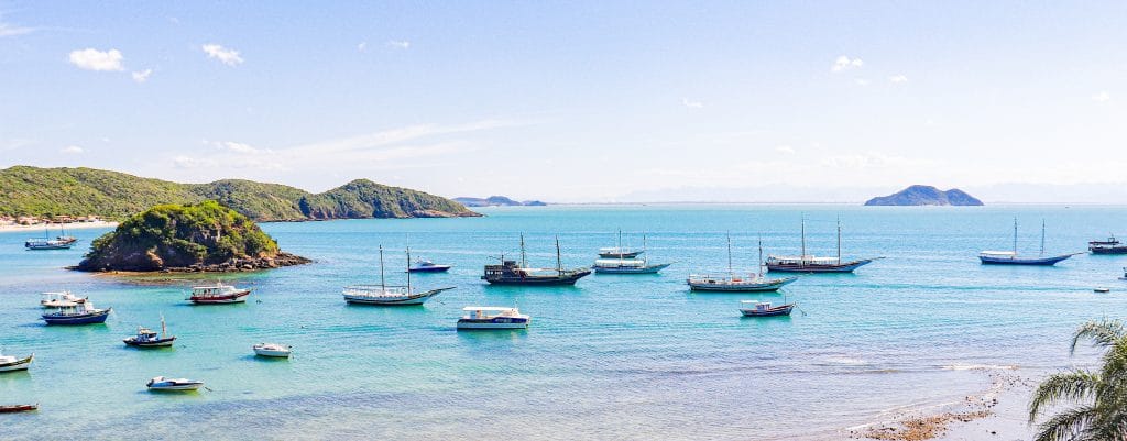 Vista panorâmica de hotel de luxo em Búzios mostra mar com vários barcos e uma ilha