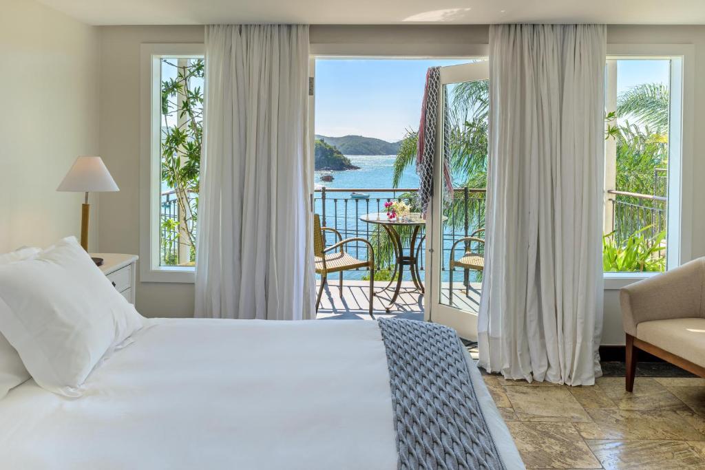 Quaro com colcha branca e varandinha com vista para o mar em Búzios