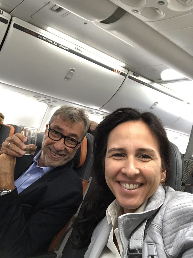 Casal sorrindo para foto dentro de avião em viagem sabática