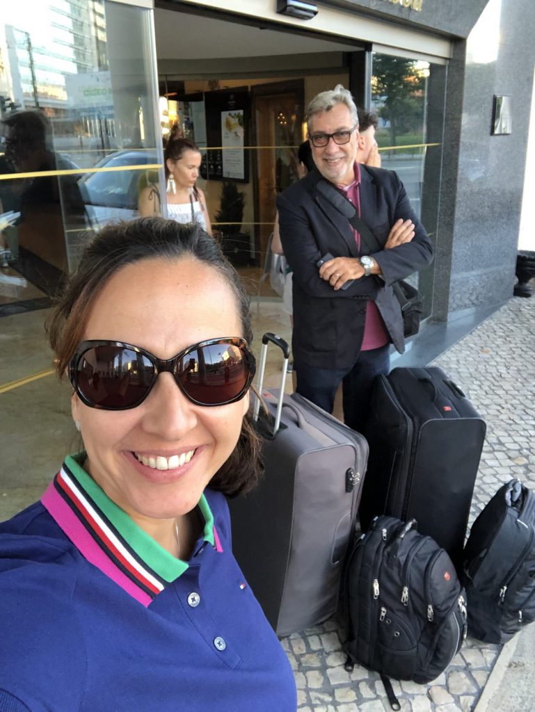 Casal na porta de hotel em Lisboa com malas grandes.