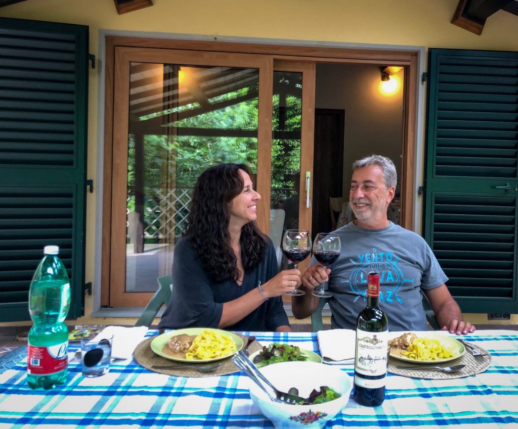 casal brindando com vinho tinto em jantar na varanda de casa na Toscana em viagem sabática