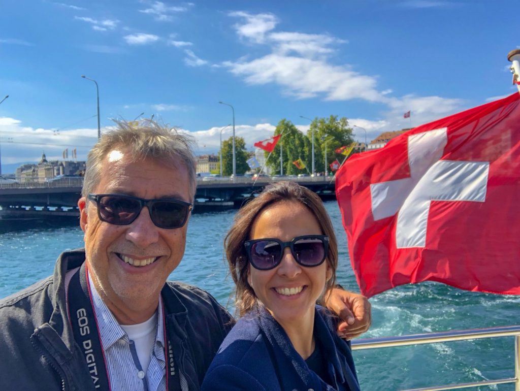 Casal passeando de barco em Genebra com bandeira da Suíça ao fundo