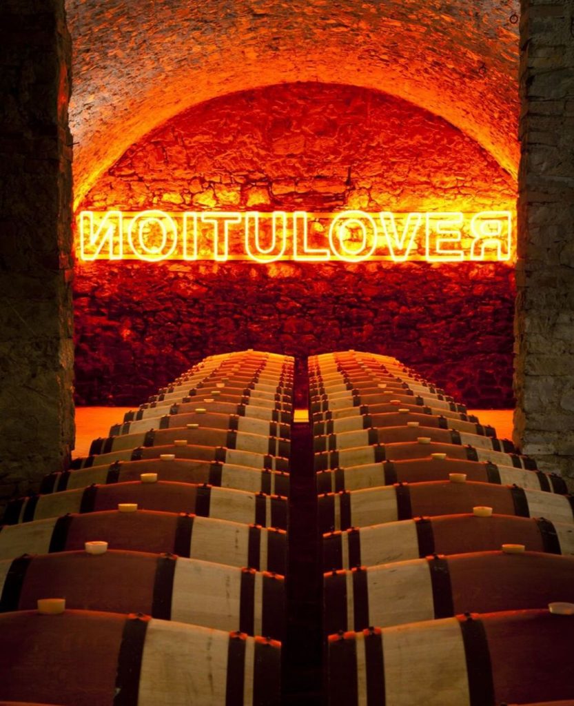 Barricas de vinho com obra de arte ao fundo